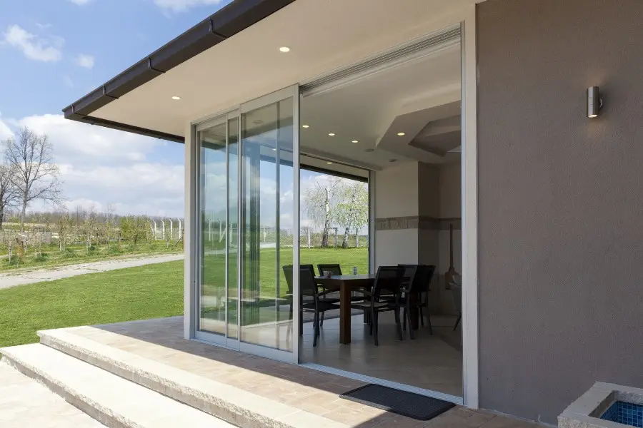 Energy-efficient modern home with sliding glass doors opening to a landscaped garden, symbolising the benefits of PAS 2030-certified installations.