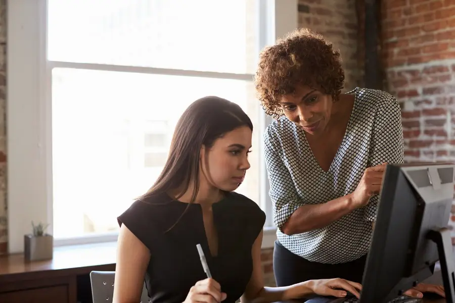 Two professionals reviewing documents on a computer representing ISO 9001 audit findings and corrective actions for quality management compliance
