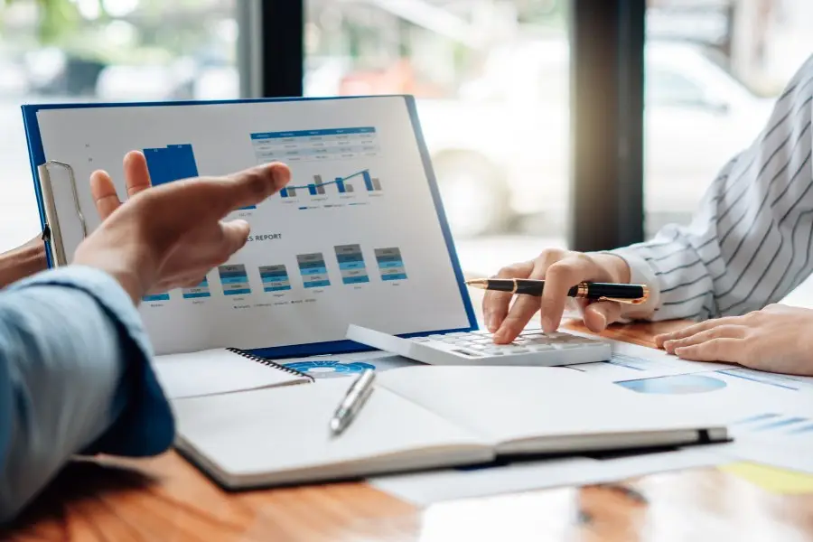 Two professionals reviewing performance charts and quality data in a business meeting, symbolising how ISO 9001 is used to monitor, measure, and improve organisational performance. The image conveys data-driven decision-making and quality management in action.