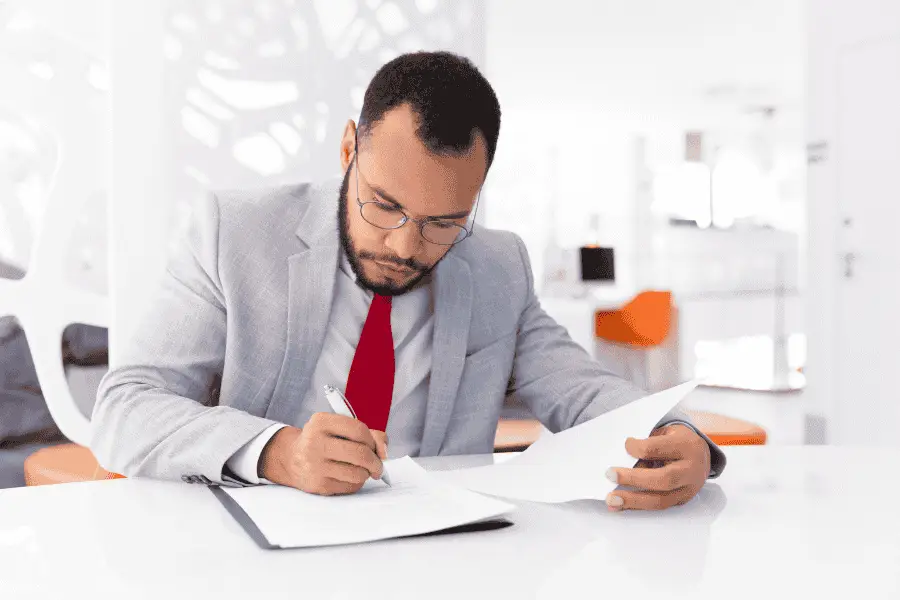 Auditor reviewing documents and making notes during a quality management system assessment.